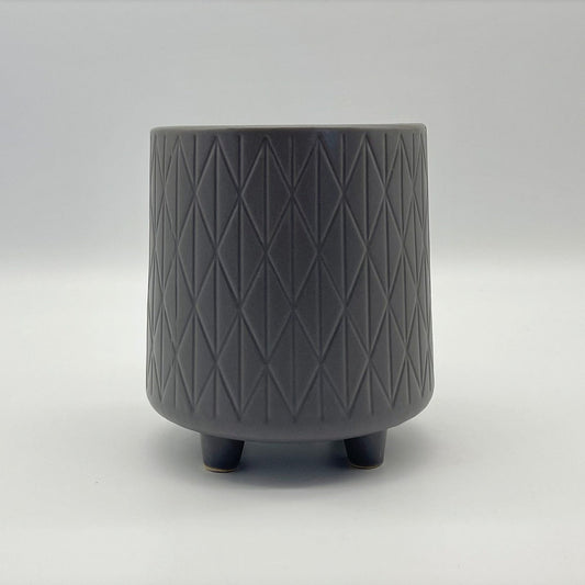 The Easygoing One grey ceramic planter with geometric texture and small feet, shown on a neutral background.