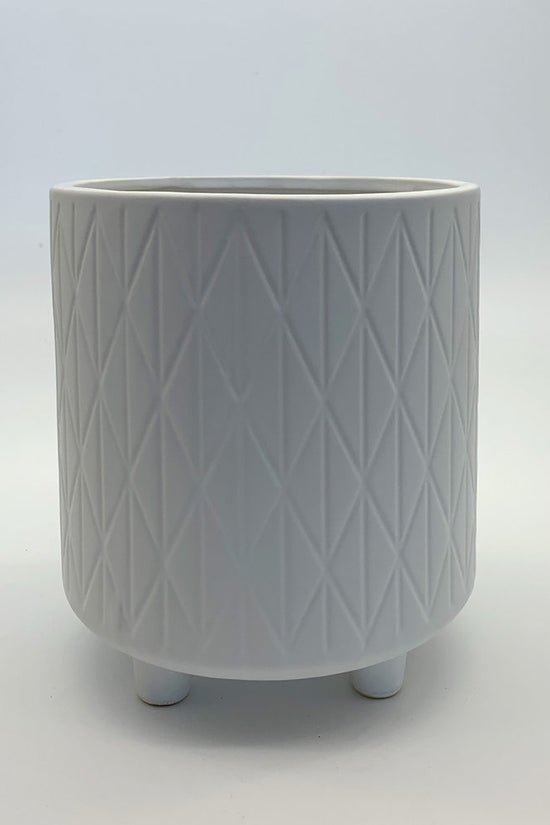 The Easygoing One white ceramic planter featuring a soft geometric pattern and small rounded feet, photographed on a clean gradient background.
