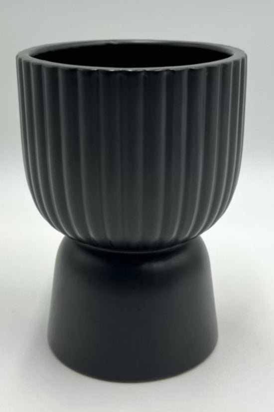 The Good Egg black ribbed ceramic planter with a pedestal base, photographed against a white background.