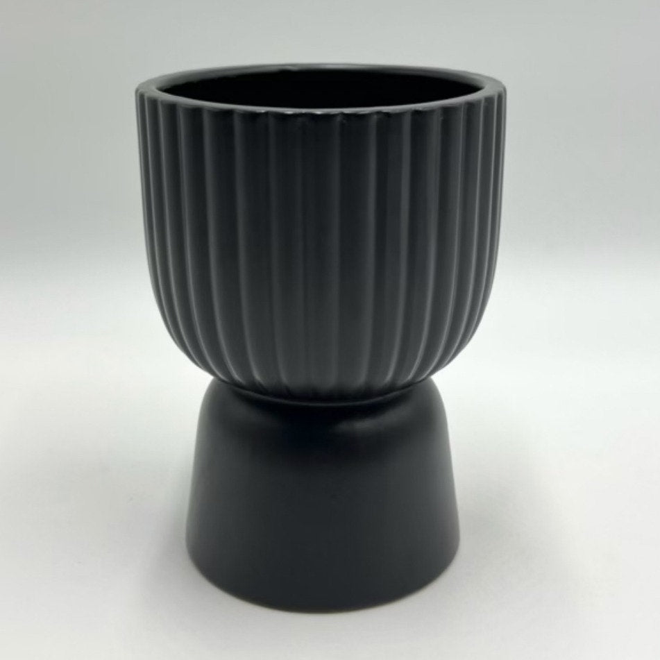 The Good Egg black ribbed ceramic planter with a pedestal base, photographed against a white background.