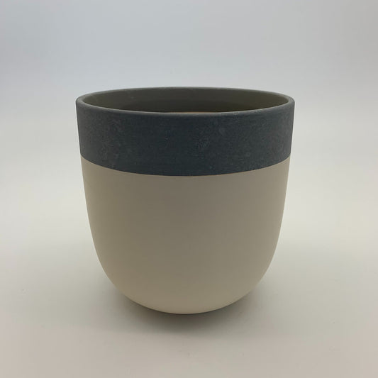 The Quiet One two-tone planter featuring a charcoal top band and light beige base, photographed on a clean white background.