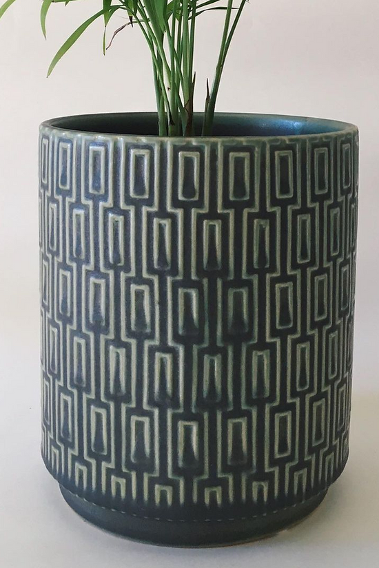 The Side Table Star planter in blue with a raised geometric pattern, shown holding a plant against a white background.