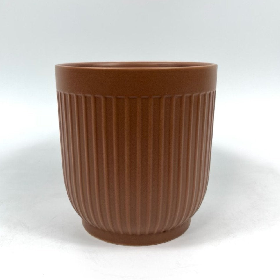 The Soft Shape planter in warm terracotta with ribbed sides and a matte finish on a white backdrop.