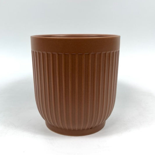 The Soft Shape planter in warm terracotta with ribbed sides and a matte finish on a white backdrop.