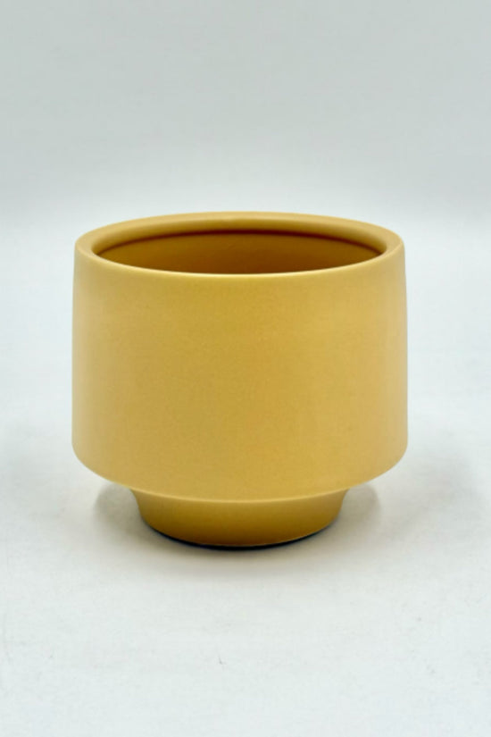 The Soft Spoken planter in mustard yellow with a smooth matte finish and raised base, photographed on a white background.
