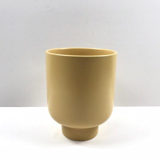 The Sunday Pot in mustard yellow with a raised pedestal shape and matte texture photographed on white.